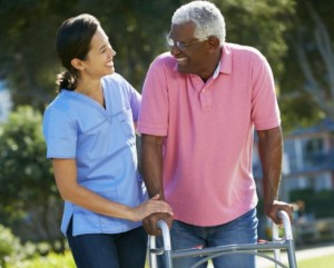 Carer Helping Senior Man With Walking Frame